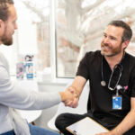 A male doctor is shaking the hand of a patient