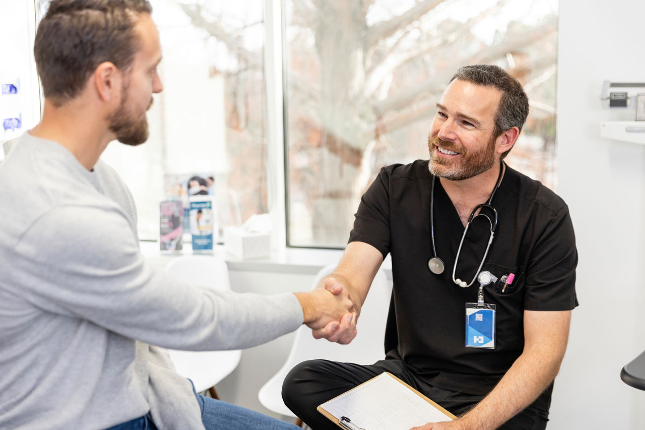 A male doctor is shaking the hand of a patient